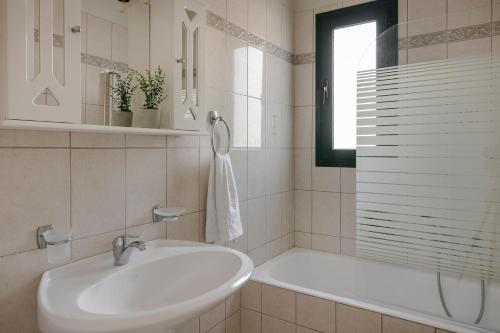 un bagno bianco con lavandino e vasca di Seaspray Villa Kefaloniaprivatevillas a Cefalonia