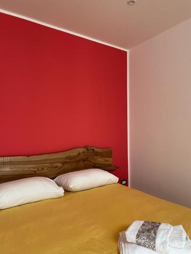 um quarto com uma parede vermelha e uma cama com duas almofadas em Il sette e l'otto em Caiazzo
