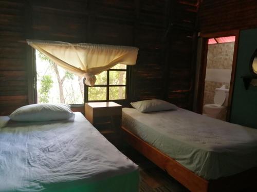 2 Betten in einem Zimmer mit Fenster in der Unterkunft Rancho paola in Cotuí