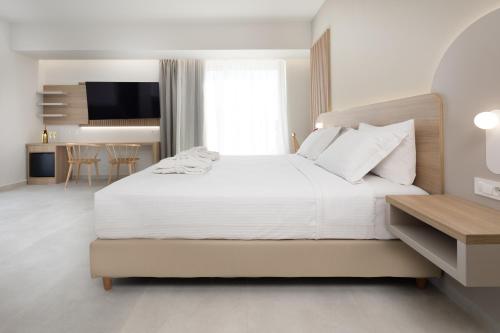 a white bedroom with a large bed and a table at Epavli Grace Hotel in Chania Town