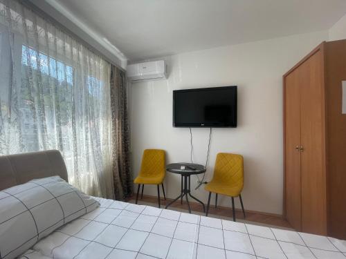 a bedroom with a bed and two chairs and a tv at Studio Apartman Centar in Zenica