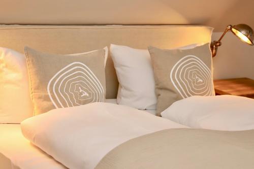 a bed with white pillows and a lamp on a table at HaffSide Usedom in Zirchow