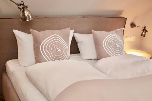 a bed with white and gray pillows at HaffSide Usedom in Zirchow