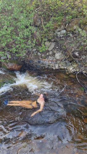 una persona tirada en el agua en un arroyo en Øyfoss overnatting en Fyresdal