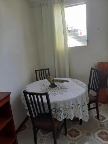 uma mesa com uma toalha de mesa branca com quatro cadeiras em LE RELAIS DES 4 b-SAISONNIER em Le Gosier