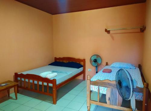 a bedroom with two beds and a fan on the wall at Rustic House Hostel in Moyogalpa