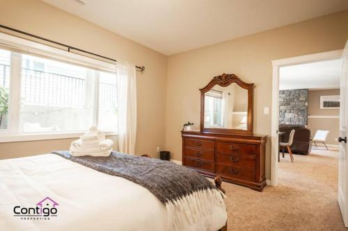 a bedroom with a bed and a mirror and a dresser at Luxury Retreat, Sleeps 12, AC, Patio, 5 min to YQL in Lethbridge
