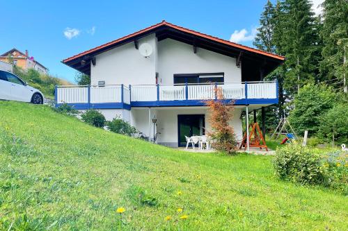 uma casa branca com uma varanda numa colina em Haus Waldblick em Philippsreut