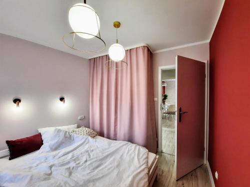 a bedroom with a white bed and a red wall at Apartament Kwietniewskiego 4 Bytom in Bytom