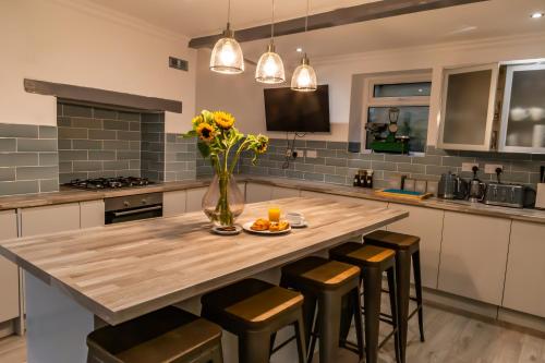 a kitchen with a large wooden table with a vase of flowers at Detached Luxury 6 beds, Super Wi-fi, easy parking and Hot-tub in Baildon