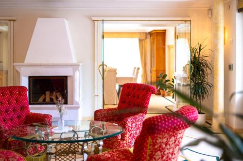uma sala de estar com cadeiras vermelhas e uma mesa de vidro em B&B Das Land-Palais - PRIVATE Mountain Hideaway em Selva dei Molini