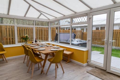 a dining room with a table and chairs in a conservatory at Spacious Cottage with Private Hot Tub in Baildon