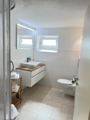 a white bathroom with a sink and a toilet at Appartement Am Straßland in Kirchheim