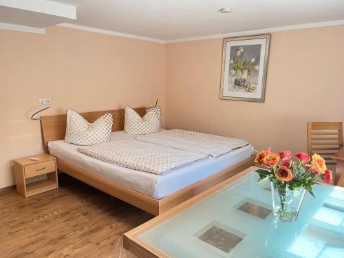 a bedroom with a bed and a glass table with flowers at Appartement Am Straßland in Kirchheim