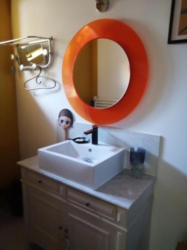 um espelho laranja sobre um lavatório branco na casa de banho em Maison d'Art' lette em Saint-Féliu-dʼAvall