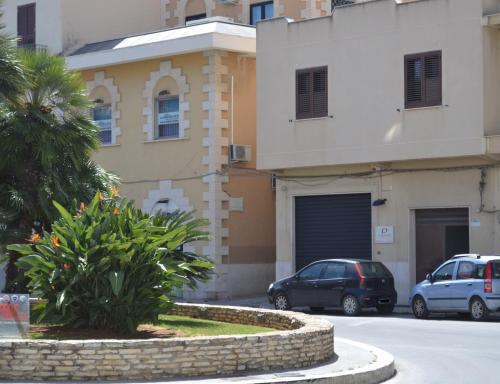 a building with cars parked in front of a street at Bilocale Giacomo Matteotti in Mazara del Vallo