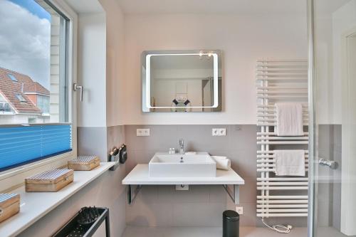 La salle de bains est pourvue d'un lavabo et d'un miroir. dans l'établissement Haus Sommertraum Haus Sommertraum, Appartement 6 "Sonnendeck", à Haffkrug