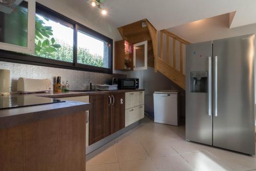 a kitchen with a stainless steel refrigerator and wooden cabinets at La Résidence de Lorelei in Cierp