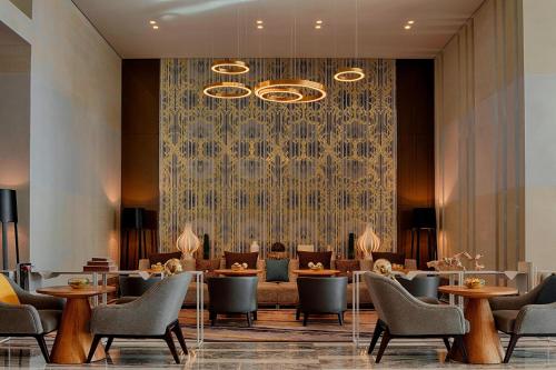 a hotel lobby with tables and chairs and a wall at Le Meridien City Centre Bahrain in Manama