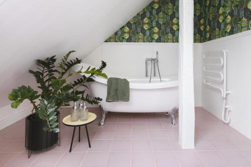 een badkamer met een wit bad en een potplant bij Chata Patykowo in Myślenice