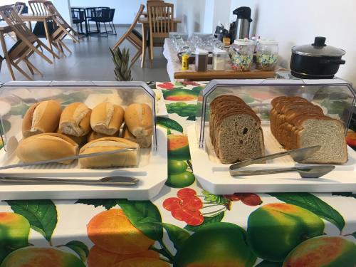 duas bandejas de sanduíches e pão numa mesa em Foca Guest House em Búzios