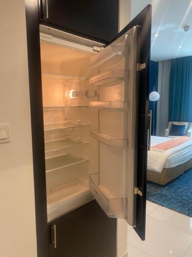 a refrigerator with its door open in a bedroom at Квартира студия Damac Maison Cour Jardin in Dubai