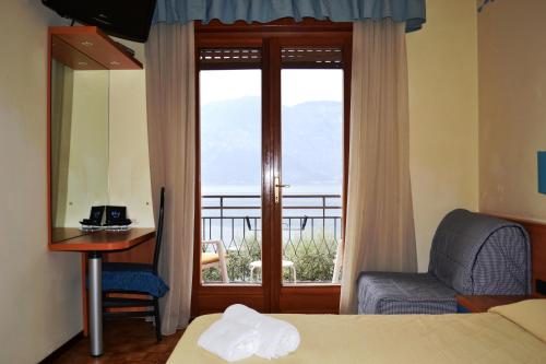 una camera d'albergo con un letto, una sedia e una finestra di Hotel Smeraldo a Brenzone sul Garda