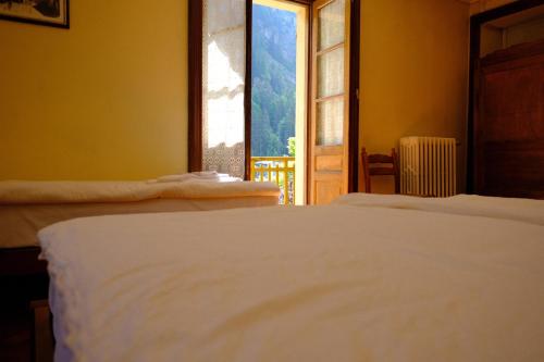 two beds in a room with a view of a window at Hotel Villa Tedaldi in Gressoney-Saint-Jean