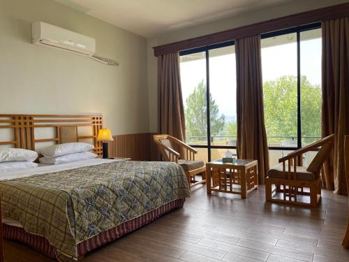 a hotel room with a bed and a large window at Rock City Resort in Mingora