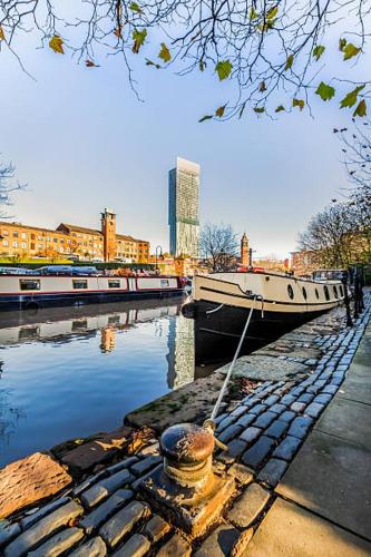 un barco atracado en un río con edificios en el fondo en Minimalist space - Manchester City Centre, en Mánchester