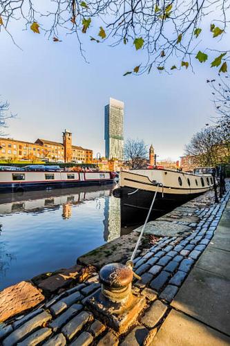 a boat docked on a river with buildings in the background at Minimalist space - Manchester City Centre in Manchester