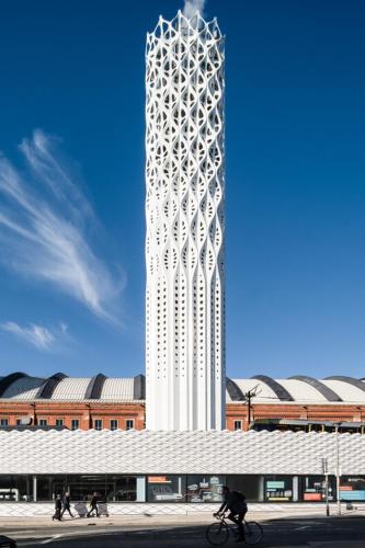 een persoon op een fiets voor een hoge toren bij Minimalist space - Manchester City Centre in Manchester