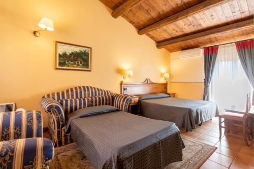 a living room with two chairs and a couch and a bed at Hotel Il Barocco in Ragusa