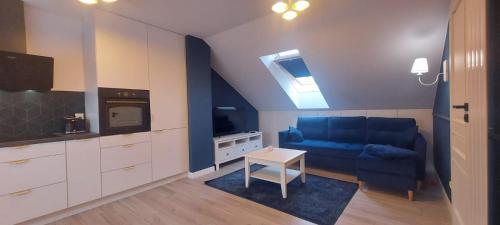 ein Wohnzimmer mit einem blauen Sofa und einem TV in der Unterkunft Kameralny Apartament nieopodal Gdyni parking NEW in Pogórze