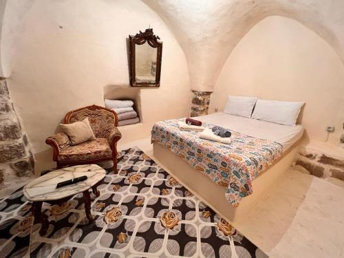 ein Schlafzimmer mit einem Bett, einem Stuhl und einem Spiegel in der Unterkunft Acabey Konuk Evleri in Mardin