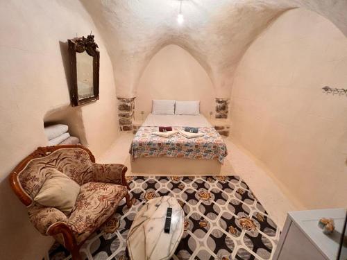 ein Schlafzimmer mit einem Bett und einem Stuhl in einem Zimmer in der Unterkunft Acabey Konuk Evleri in Mardin