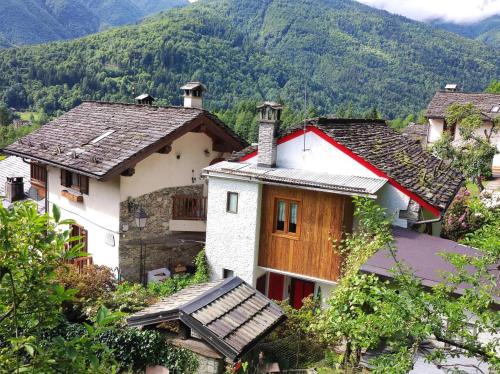 une maison sur une colline avec des montagnes en arrière-plan dans l'établissement La baita alpina, à Scopello