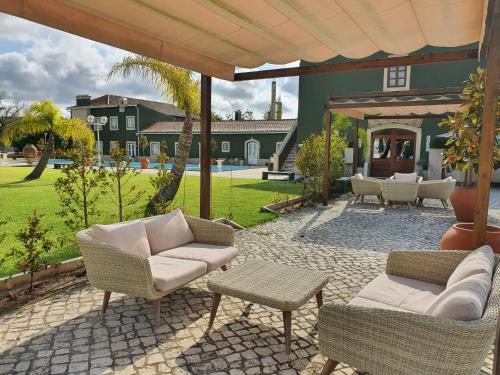 una casa y un patio con sillas y mesas. en Quinta do Pinheiro Hotel Rural - GQL en Valado dos Frades