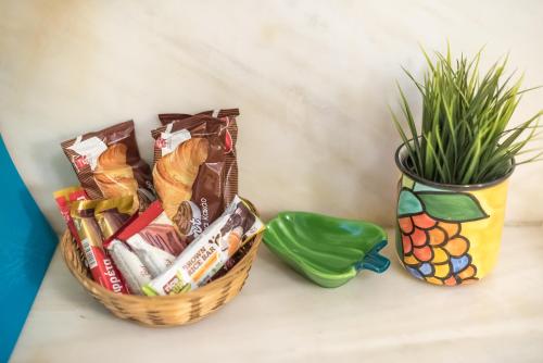 a basket of snacks next to a vase with a plant at Sweet home in Koukaki in Athens