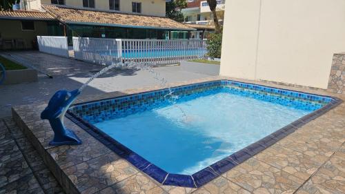 a pool with a dolphin water fountain at Quintal do forte in Praia Grande