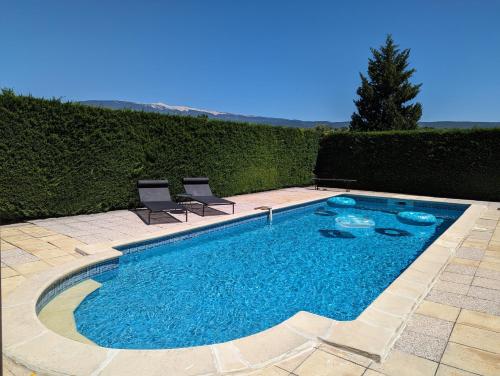 a swimming pool with two chairs sitting next to it at Gîte Les Murmures du Ventoux in Mormoiron