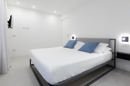 a bedroom with a large white bed with blue pillows at A - MARE Home Catania in Catania