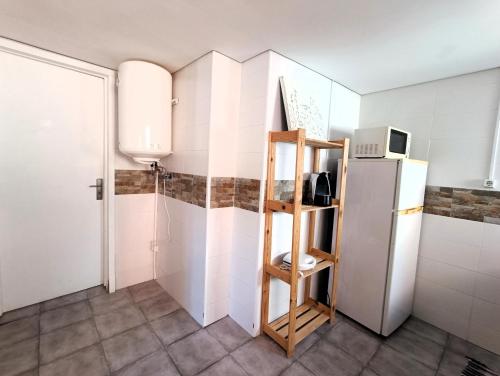 a kitchen with a white refrigerator and a shelf at Bonjoia Apartments in Porto