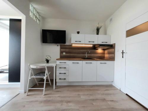 a kitchen with white cabinets and a table and a tv at VIP Centrum Apart in Krakow