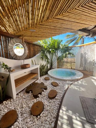 a garden with rocks and a pool with a wooden ceiling at BAMBU BLU Lagoon Homes in Itarema