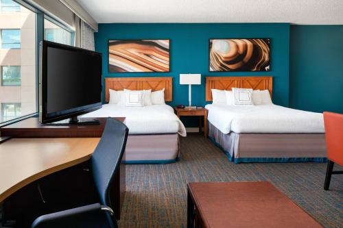 a hotel room with two beds and a desk with a tv at Residence Inn by Marriott Las Vegas Hughes Center in Las Vegas