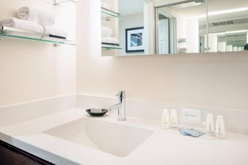 Baño blanco con lavabo y espejo en Residence Inn by Marriott Las Vegas Hughes Center, en Las Vegas