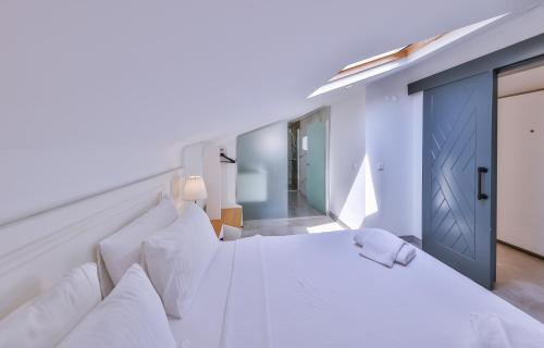 a white bedroom with a large white bed with a blue door at Hemera Suite in Kas