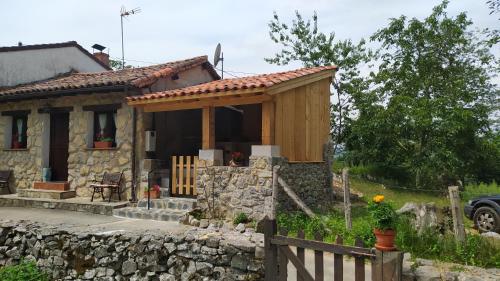 una pequeña casa de piedra con una valla delante en La Casa de la Vieja, en Nava