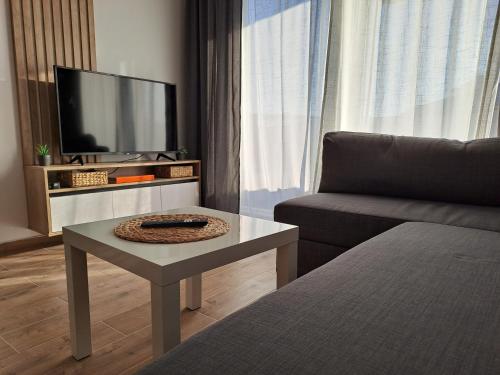 a living room with a couch and a table and a tv at Apartman 64 Lux in Veliko Gradište